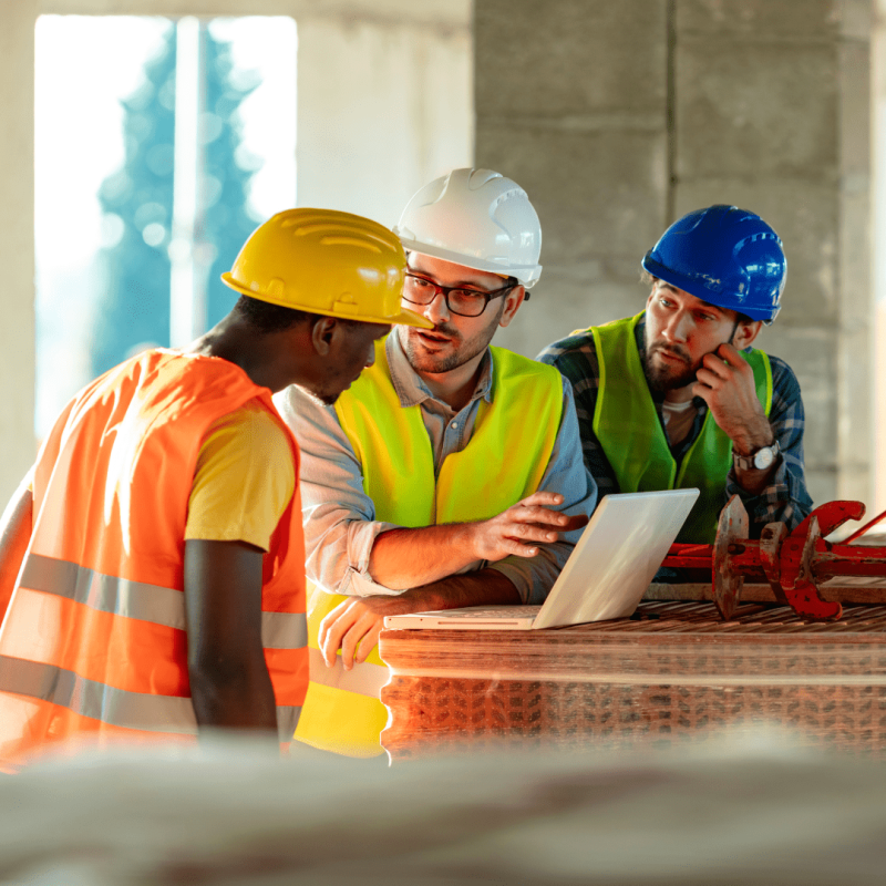workmen talking whilst looking at computer