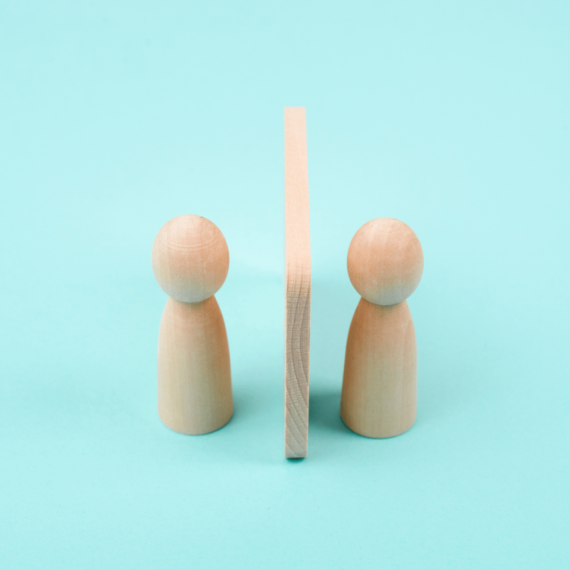 two wooden people with a wooden wall inbetween